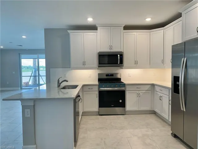 Kitchen featuring white cabinets, sink, kitchen peninsula, stainless steel appliances, and decorative backsplash