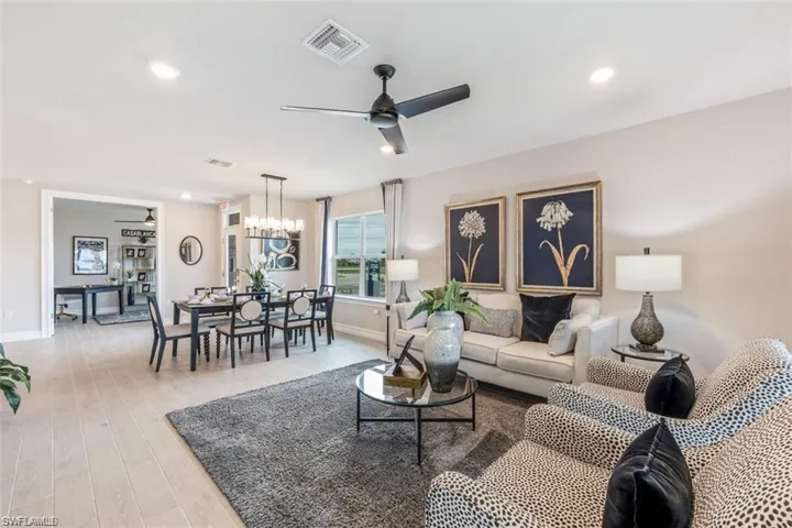 Living room with ceiling fan with notable chandelier and light wood-type flooring