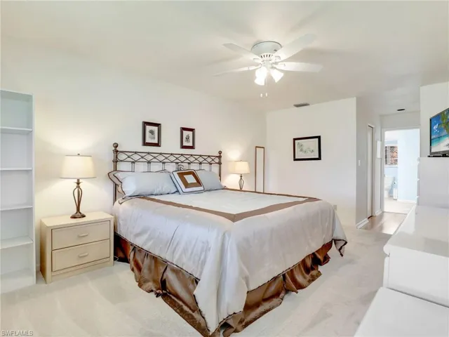 Carpeted bedroom with ensuite bath and ceiling fan