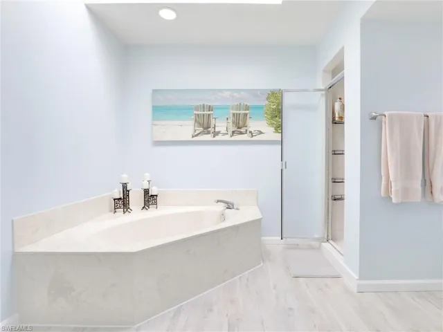 Bathroom featuring separate shower and tub, a water view, and hardwood / wood-style flooring