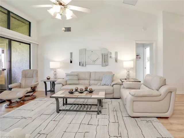 Living room featuring high vaulted ceiling, light hardwood / wood-style floors, and ceiling fan