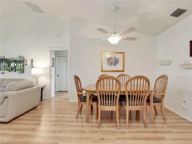 Dining space with ceiling fan, high vaulted ceiling, and light hardwood / wood-style flooring