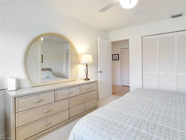 Bedroom with a closet, light colored carpet, and ceiling fan