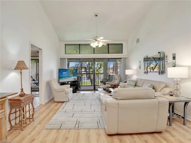 Living room featuring high vaulted ceiling, light wood-type flooring, and ceiling fan