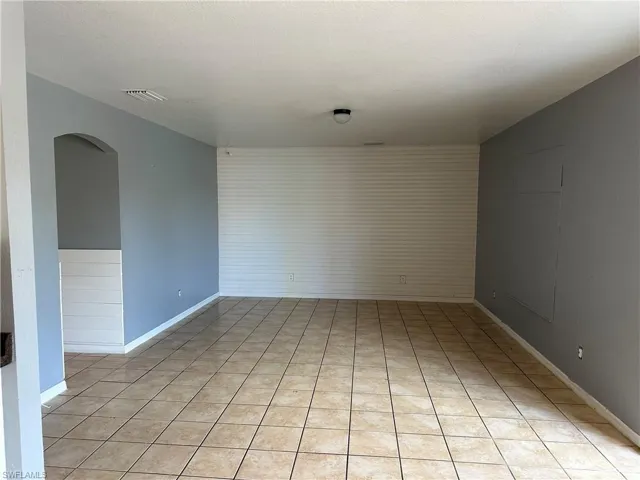 Tiled spare room featuring wood walls and a textured ceiling