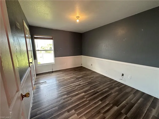 Spare room featuring a textured ceiling and dark hardwood / wood-style floors