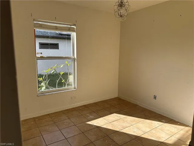 Tiled empty room featuring an inviting chandelier