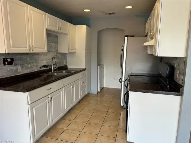 Kitchen featuring light tile patterned flooring, white cabinetry, decorative backsplash, sink, and custom exhaust hood