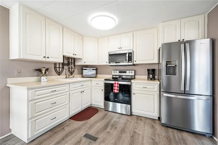 Kitchen featuring stainless steel appliances, light countertops, light wood-type flooring, and white cabinetry
