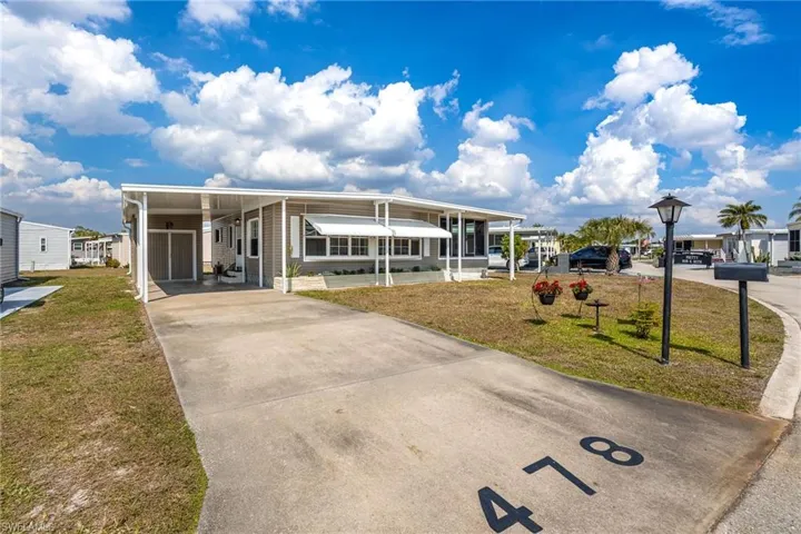 Manufactured / mobile home with a front lawn, concrete driveway, and a carport