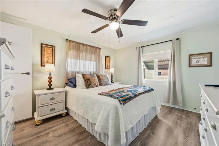 Bedroom with multiple windows, dark wood-style flooring, and ceiling fan