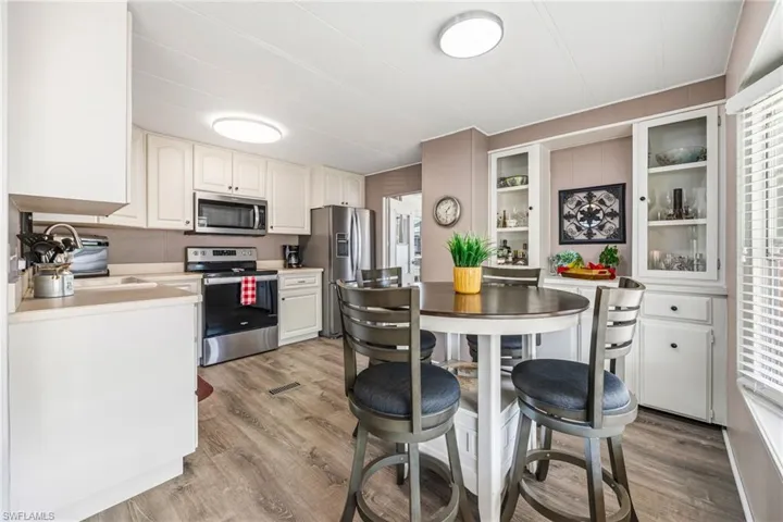 Kitchen featuring stainless steel appliances, light countertops, white cabinets, and light wood-style floors