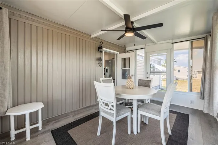 Sunroom / solarium with ceiling fan, beam ceiling, and outdoor dining space