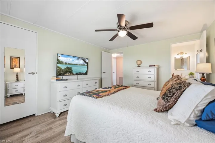 Bedroom with light wood finished floors, ceiling fan, connected bathroom, and crown molding