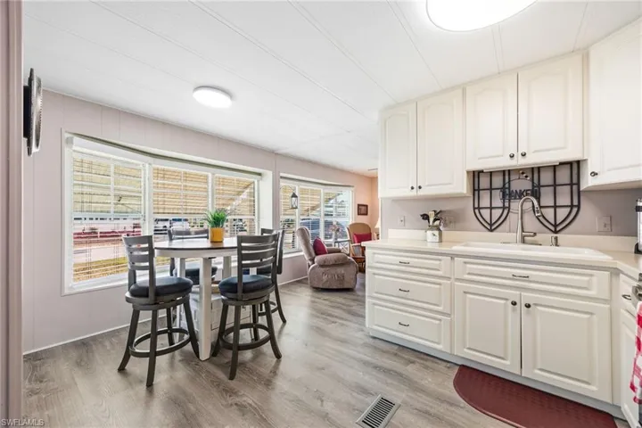 Kitchen featuring light wood-style flooring, white cabinets, and light stone counters