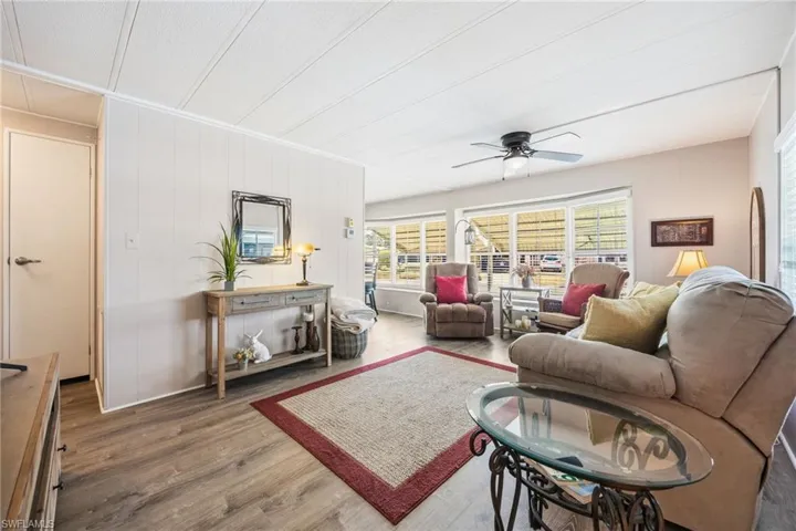 Living area featuring wood finished floors, a ceiling fan, and wooden walls