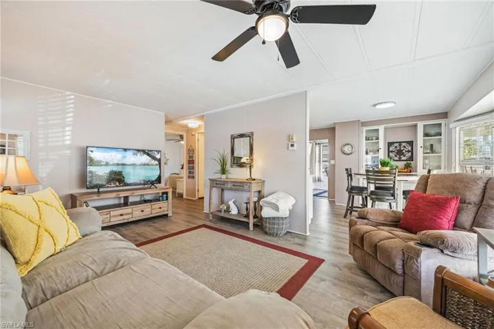 Living room with ceiling fan, wood finished floors, and ornamental molding