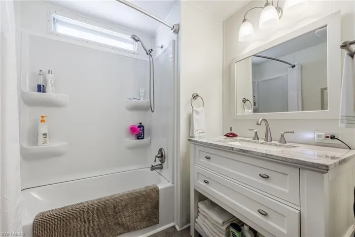Full bathroom with vanity, shower / tub combo, and ornamental molding