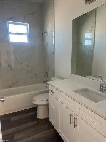 Full bathroom with hardwood / wood-style floors, vanity, toilet, and tiled shower / bath