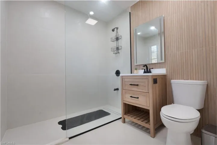 Bathroom featuring vanity, walk in shower, and tile walls