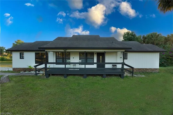 Front view of house with a lawn, covered porch, and a shingled roof