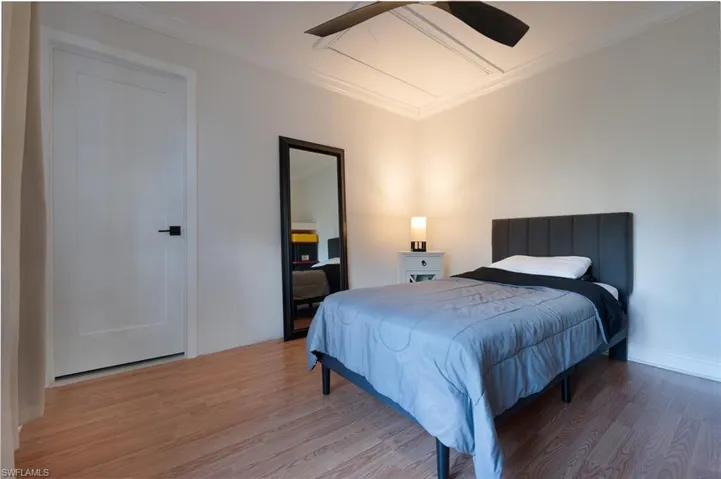 Bedroom with wood finished floors, crown molding, and ceiling fan
