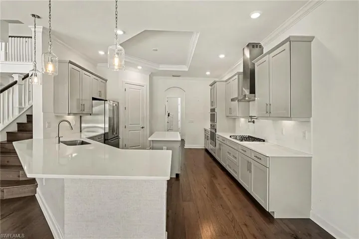 QUARTZ COUNTER TOPS.  TALL CABINETS.  STAINLESS STEEL APPLIANCES.  GAS STOVE.  STAINLESS STEEL RANGE HOOD. POT FILLER.  WALL OVEN AND MICROWAVE.  PENDANT AND RECESSED LIGHTING.  UNDER CABINET LIGHTING.  FINISHED PANTRY IS JUST TO RIGHT OF THE REFRIGERATOR.  WORK ISLAND.  ROOMY COUNTER-HEIGHT PENINSULA FOR CASUAL DINING.