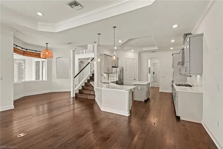 VIEW FROM FAMILY TOWARDS KITCHEN AND BREAKFAST NOOK.  ARCHED DOORWAY TO POWDER ROOM, LAUNDRY AND GARAGE SHOWN AT MIDDLE REAR.  STAIRCASE LEADS TO UPSTAIRS 3 BEDROOMS AND BONUS ROOM.