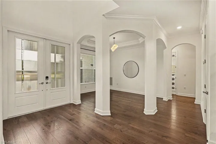 FOYER/ENTRANCE AND DINING AREA.  DECORATIVE GLASS DOORS. RICH WOOD LOOK FLOORING THROUGHOUT.  AT RIGHT REAR IS THE ENTRANCE TO THE POWDER ROOM, LAUNDRY AND GARAGE.
