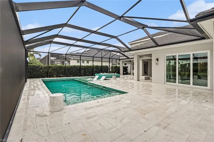 TRAVERTINE POOL DECK.  3-PANEL SLIDING DOORS LEAD TO FAMILY ROOM.