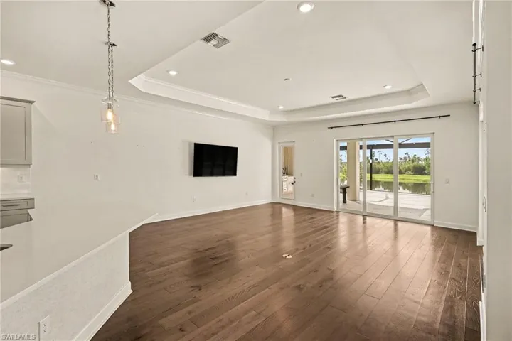 FAMILY ROOM.  3-PANEL SLIDING DOORS PLUS WOOD-FRAMED GLASS DOOR TO OUTDOOR LIVING AREA.  KITCHEN IS TO RIGHT.  FLOATING ELECTRIC OUTLET IN FLOOR.