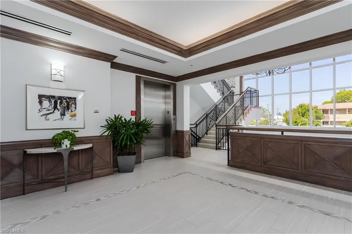 Lobby area featuring light tile flooring with decorative inlay, extensive dark wood paneling, and a full-height window wall