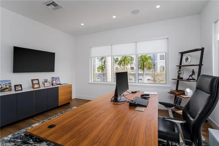 Dedicated office space featuring wood-finish flooring, recessed lighting, and a window with roller shades