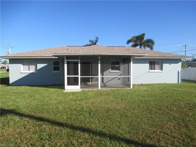 Rear view of house with a yard and a sunroom