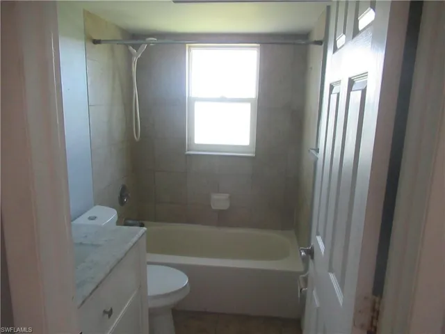 Full bathroom with vanity, tiled shower / bath combo, and toilet