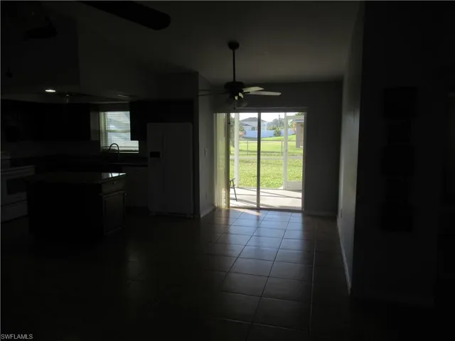 Kitchen featuring white fridge with ice dispenser, range, dark tile patterned floors, and a wealth of natural light