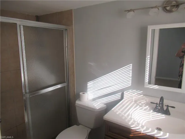 Bathroom featuring toilet, walk in shower, and vanity