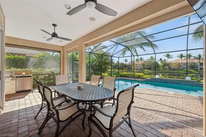 View of swimming pool featuring a water view, a patio area, ceiling fan, and a lanai