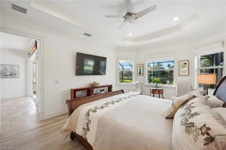 Bedroom featuring light wood-type flooring, a raised ceiling, ceiling fan, and ornamental molding