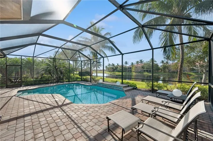 View of pool featuring a patio, a water view, and glass enclosure