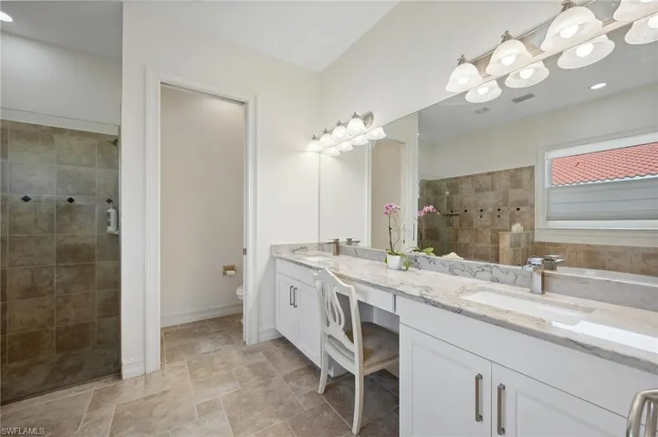 Bathroom with a tile shower, vanity, and toilet