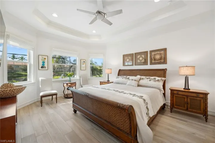 Bedroom featuring ceiling fan, a raised ceiling, and light hardwood / wood-style flooring