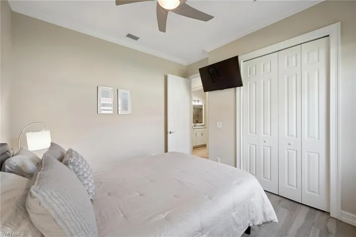 Bedroom with ceiling fan, a closet, ornamental molding, and light wood-type flooring