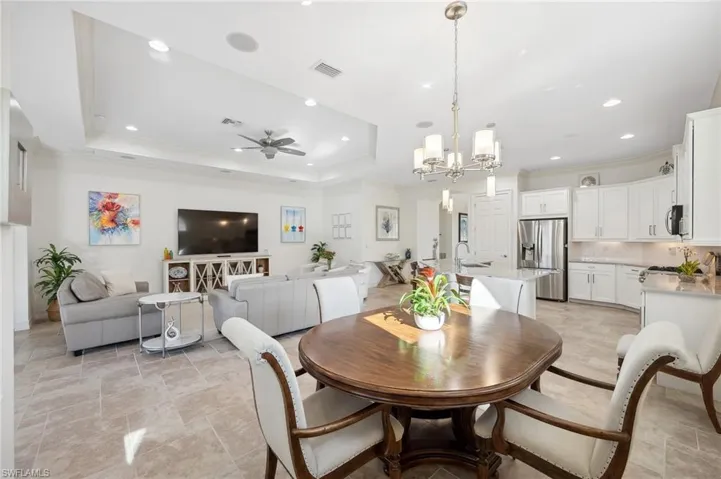 Dining room featuring a tray ceiling, sink, ceiling fan with notable chandelier, and ornamental molding