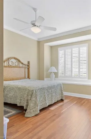 Bedroom with crown molding, ceiling fan, and hardwood / wood-style floors