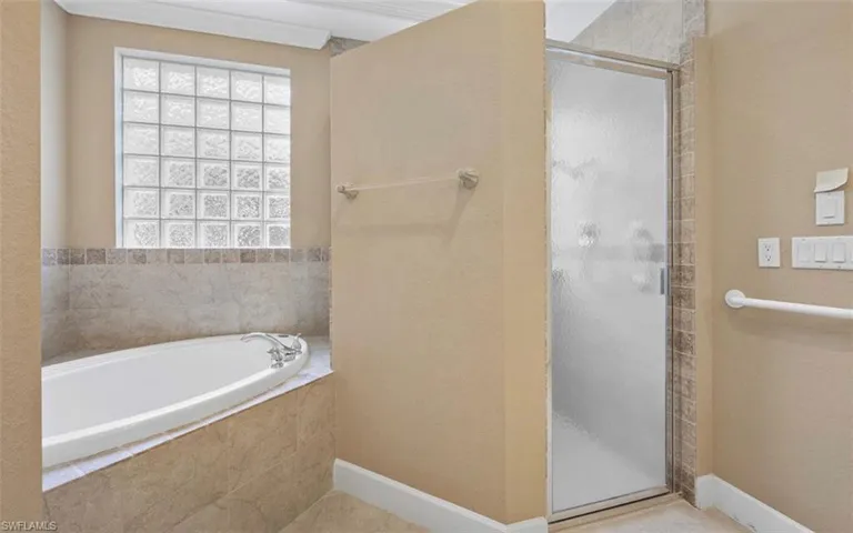 Bathroom with shower with separate bathtub and tile flooring