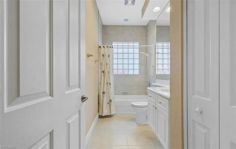 Full bathroom with shower / bathtub combination with curtain, vanity, toilet, and tile floors