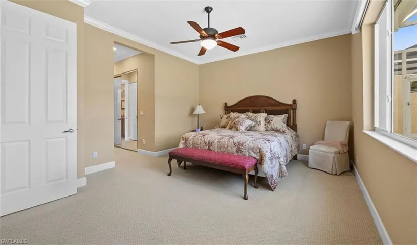 Carpeted bedroom featuring ornamental molding and ceiling fan