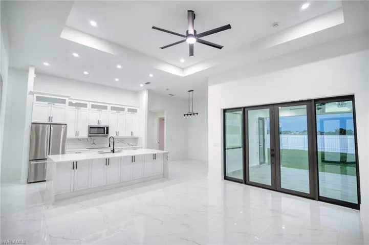 Kitchen featuring glass insert cabinets, stainless steel appliances, a large island, white cabinets, and a ceiling fan