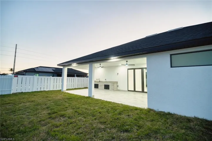 Back of property at dusk with ceiling fan, a patio, stucco siding, and roof with shingles